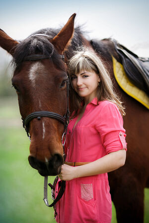 Portrait of the beautiful girl with a brown horse in parkの写真素材