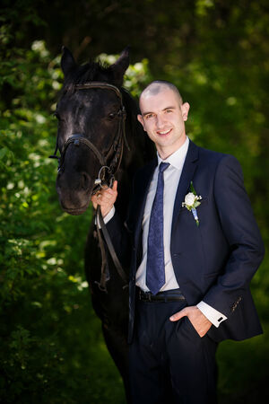 groom with black horseの写真素材