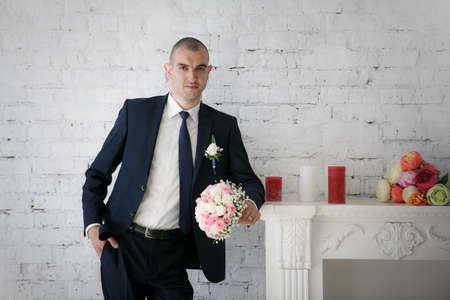 groom standing near fireplace with wedding bride bouquetの写真素材