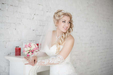 beautiful bride with wedding bouquet standing near fireplaceの写真素材