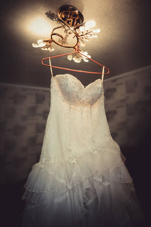 Wedding dress hanging on the chandelier in the roomの写真素材