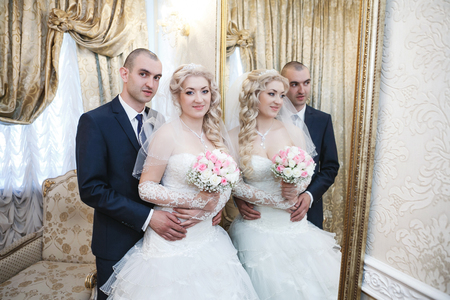 groom and the bride stand near a mirror with a gold frame and are reflected in itの写真素材
