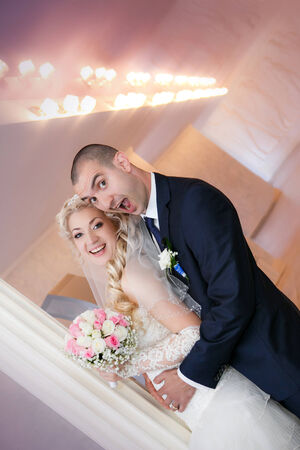 groom and the bride with a wedding bouquet stand near a white columnの写真素材