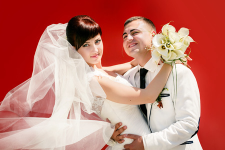 Happy groom and the bride on a red backgroundの写真素材