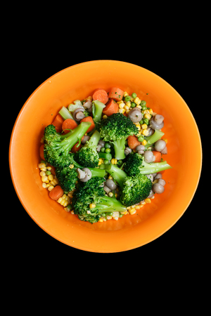 Steamed vegetables - carrots, broccoli, pepper, peas on the black backgroundの写真素材