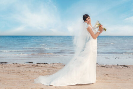 Portrait of beautiful bride standing by the beachの写真素材