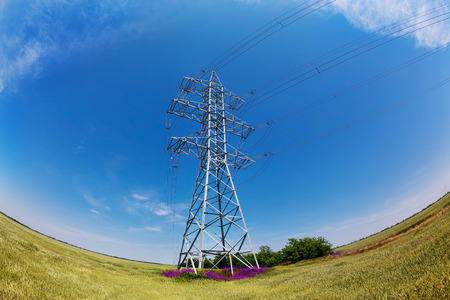 Fish-eye lens photo of high-voltage electricity pylons against blue skyの写真素材