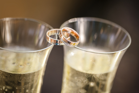 wedding rings lie on champagne glassesの写真素材