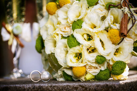 Wedding rings with wedding bouquet from beige roses, cinnamon, a lemon, a lime  and glasses of champagneの写真素材