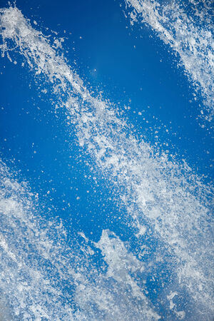 Fountain drops of pure brilliant water against a blue clear skyの写真素材