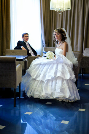 beautiful bride and the groom sit at a table in the hotel barの写真素材