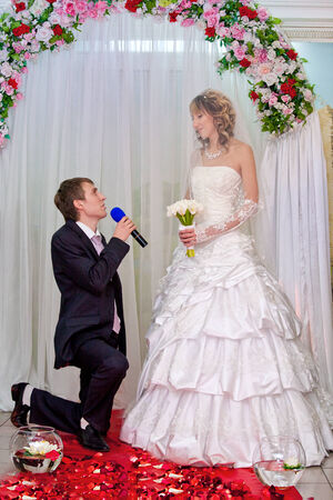happy groom kneels and does a declaration of love to the brideの写真素材