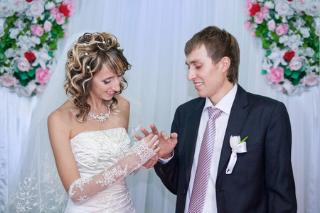 Bride putting a wedding ring on groom's fingerの写真素材