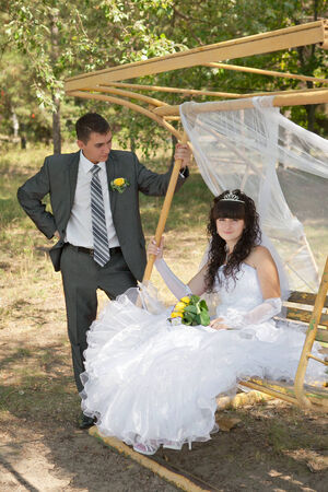 couple in love bride and groom on swing in park in their wedding dayの写真素材