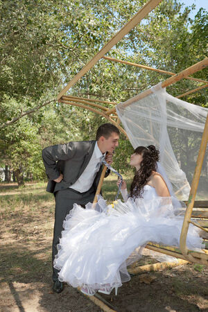 couple in love bride and groom on swing in park in their wedding dayの写真素材