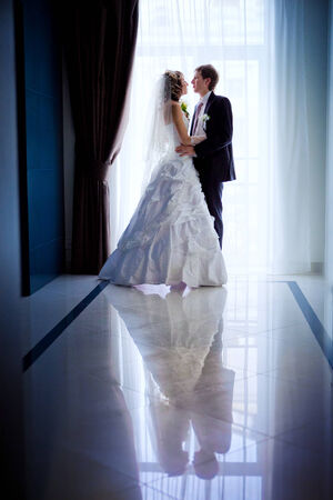 Silhouetted portrait of a bride and groom in the modern hotel hallの写真素材