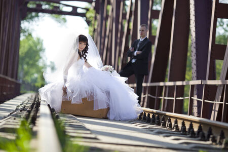 bride sits on a suitcase on the railway bridgeの写真素材