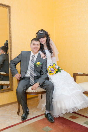 Bride and groom sitting on wooden chairの写真素材