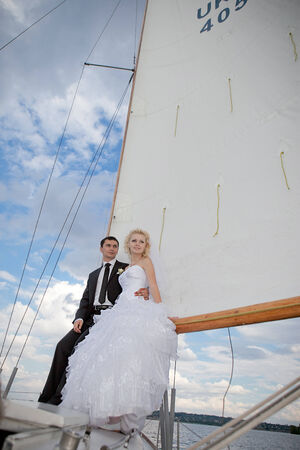 Happy bride and groom hugging on a yachtの写真素材