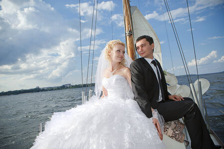 Happy bride and groom hugging on a yachtの写真素材