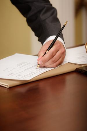 Closeup of a businessman writing on agenda left handの写真素材