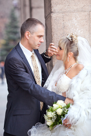 groom and the bride with a wedding bouquet stand near a white columnの写真素材