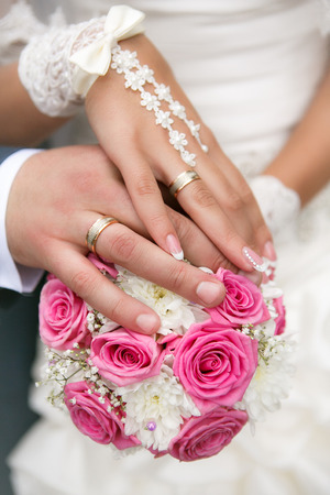 Hands and rings on wedding bouquetの写真素材