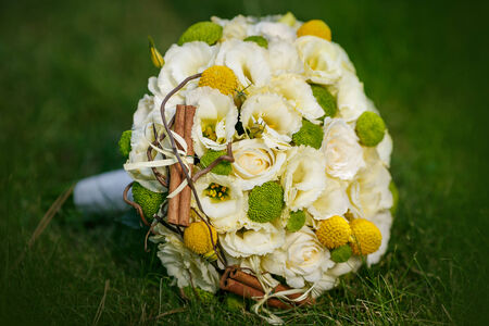 Wedding bouquet from beige roses, cinnamon, a lemon, a lime on a green grassの写真素材