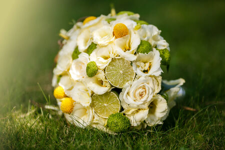 Wedding bouquet from beige roses, cinnamon, a lemon, a lime on a green grassの写真素材