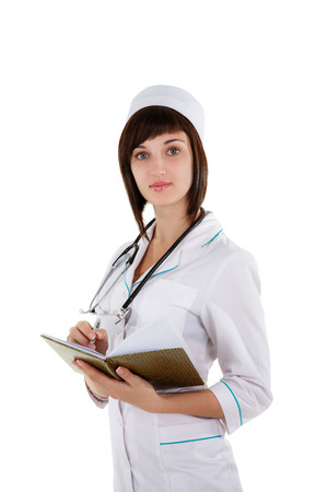 Beautiful caucasian nurse or doctor is writing in a notebook. Isolated on white.の写真素材