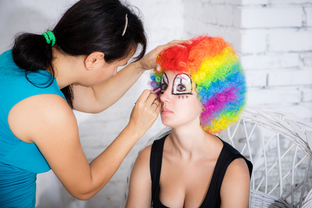 Makeup artist puts girl clown make-up in studioの写真素材