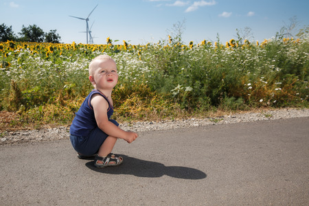 Child sits on asphalt roadの写真素材