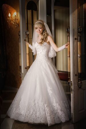 beautiful sexy bride blonde in a white dress is leaving the doorの写真素材