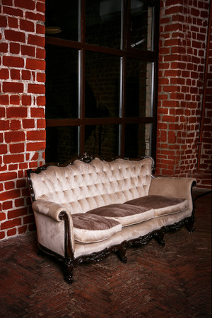 Living room with beige sofa on the  red brick wall backgroundの写真素材