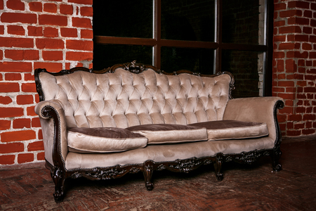 Living room with beige sofa on the  red brick wall backgroundの写真素材