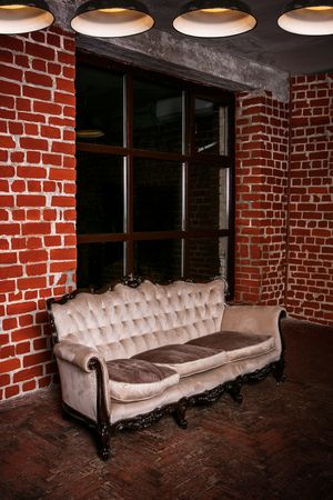 Living room with beige sofa on the  red brick wall backgroundの写真素材