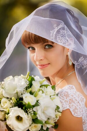 Portrait of bride with wedding bouquet in the parkの写真素材