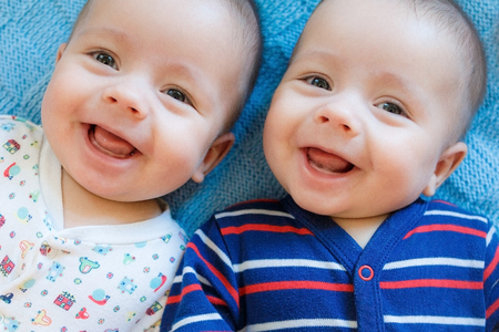Newborn twins boys are lying on the bedの写真素材