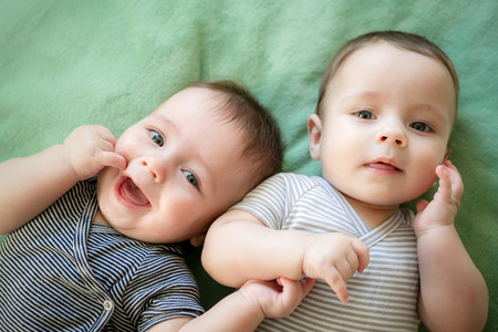 Newborn twins boys are lying on the bedの写真素材