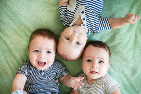 Portrait of newborn triplets are lying in the bedの写真素材