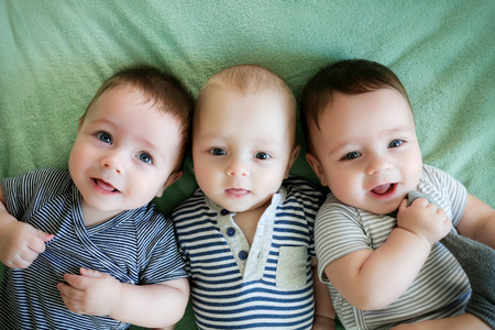 Portrait of newborn triplets are lying in the bedの写真素材