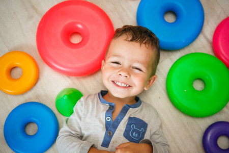 Happy little boy having fun laughing on the floor - top viewの写真素材