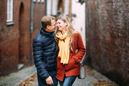 Loving couple of tourists walking around old town. Couple of lovers leisurely stroll in the cool autumn morning on the streets of a Lubeck (Germany).The guy holds his wife. Vacation, autumn, holiday, tourism: concept.の写真素材