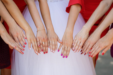 Bride and bridesmaids show bouquets of flowers. Bride and her girlfriends stand side by side and...