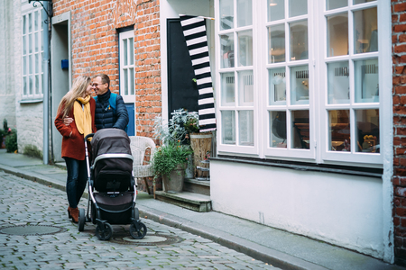 Happy young parents with baby stroller in the street of Lubeck (Germany)の写真素材