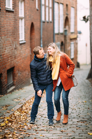 Loving couple of tourists walking around old town. Couple of lovers leisurely stroll in the cool autumn morning on the streets of a Lubeck (Germany).The guy holds his wife. Vacation, autumn, holiday, tourism: concept.の写真素材