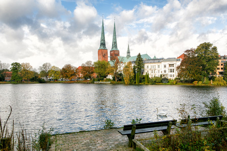 View of Lubeck The white swan is swimming in the lake. Cathedral from Muhlenteich (Mill pond) in autumn, Germany. The cathedral was started in 1173 and consecrated in 1247.の写真素材