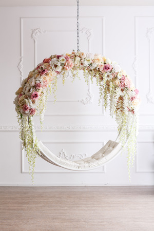 Bright spring pictures of interior of a Studio with white flowers on the swing . the decor of the room with daylight. spring photo zone.の写真素材