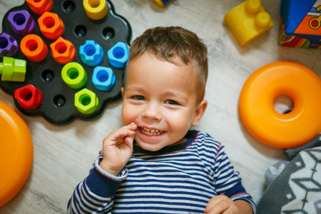 Happy little boy having fun laughing on the floor - top viewの写真素材