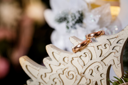 Gold wedding rings on a white wooden Christmas tree, close-up. Christmas concept.の写真素材